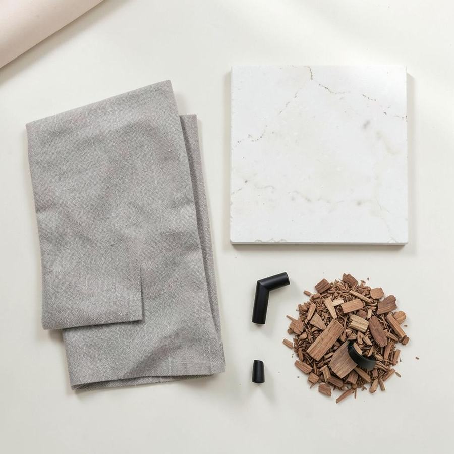 Flat lay of greige linen, white stone, oak, and matte black hardware samples