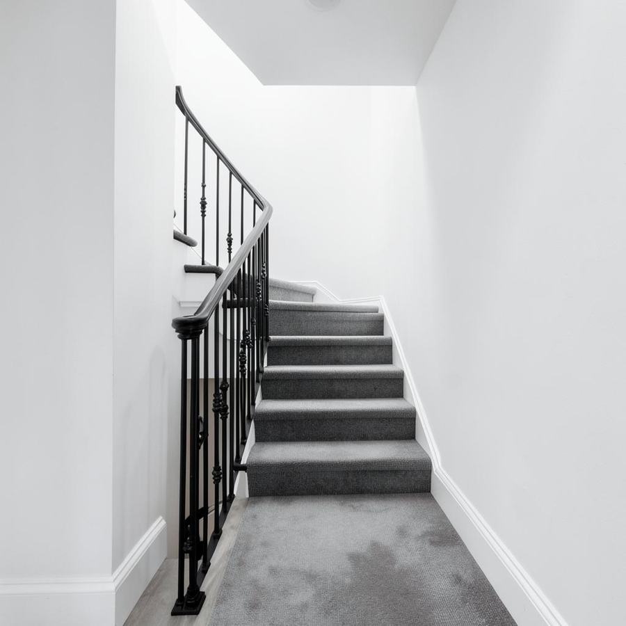 Stair hall with black iron railing and greige runner